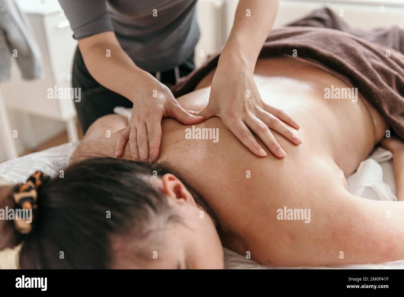 Close-up cropped photo of masseuse doing back massage on young woman on massage table in beauty salon Stock Photo