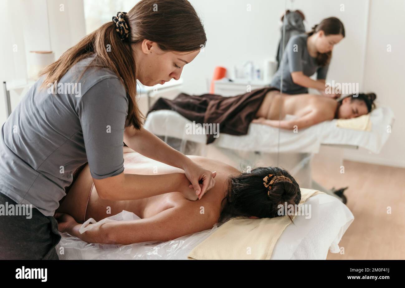 Masseuse doing back massage on young woman on massage table in beauty salon Stock Photo
