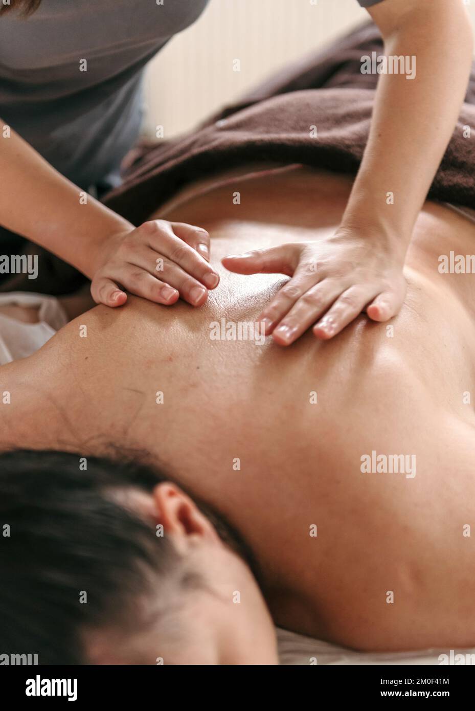 Close-up cropped photo of masseuse doing back massage on young woman on massage table in beauty salon Stock Photo