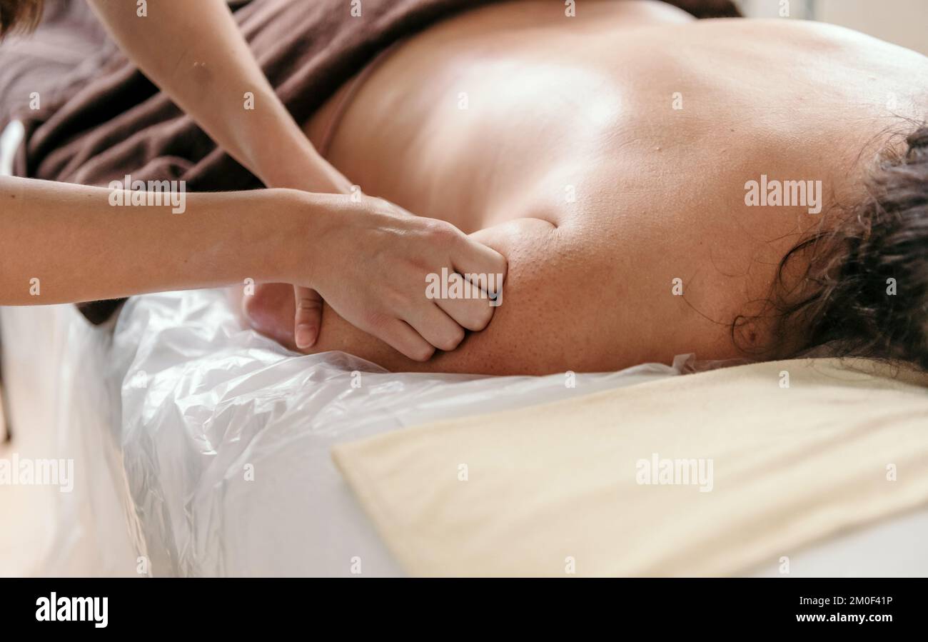 Masseuse doing shoulder massage on young woman on massage table in beauty salon Stock Photo