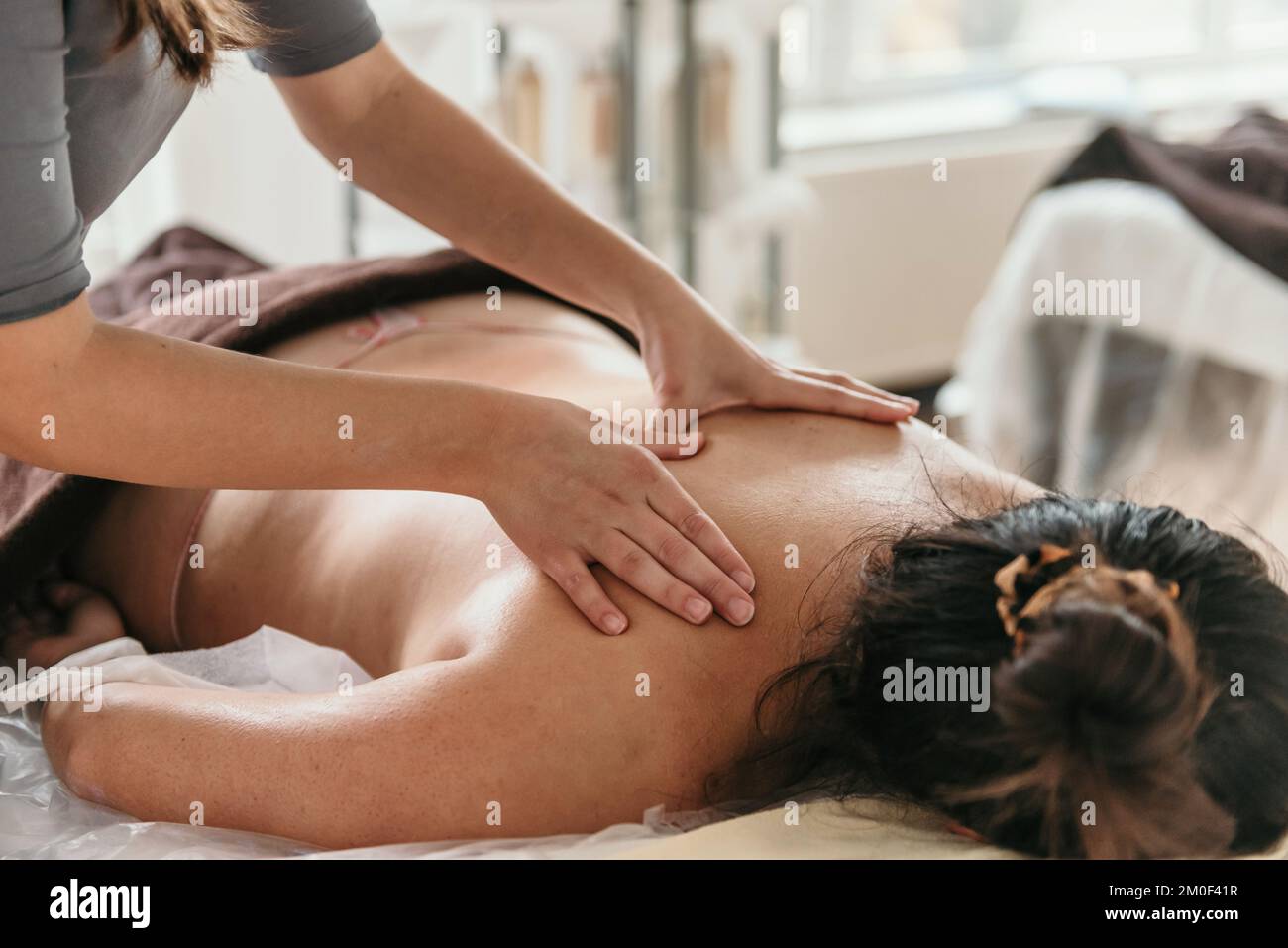 Close-up cropped photo of masseuse doing back massage on young woman on massage table in beauty salon Stock Photo