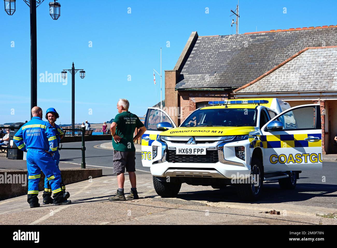 Coastguard Search and Rescue men standing by their car alongside the promenade at Pennington Point, Sidmouth, Devon, UK. Stock Photo