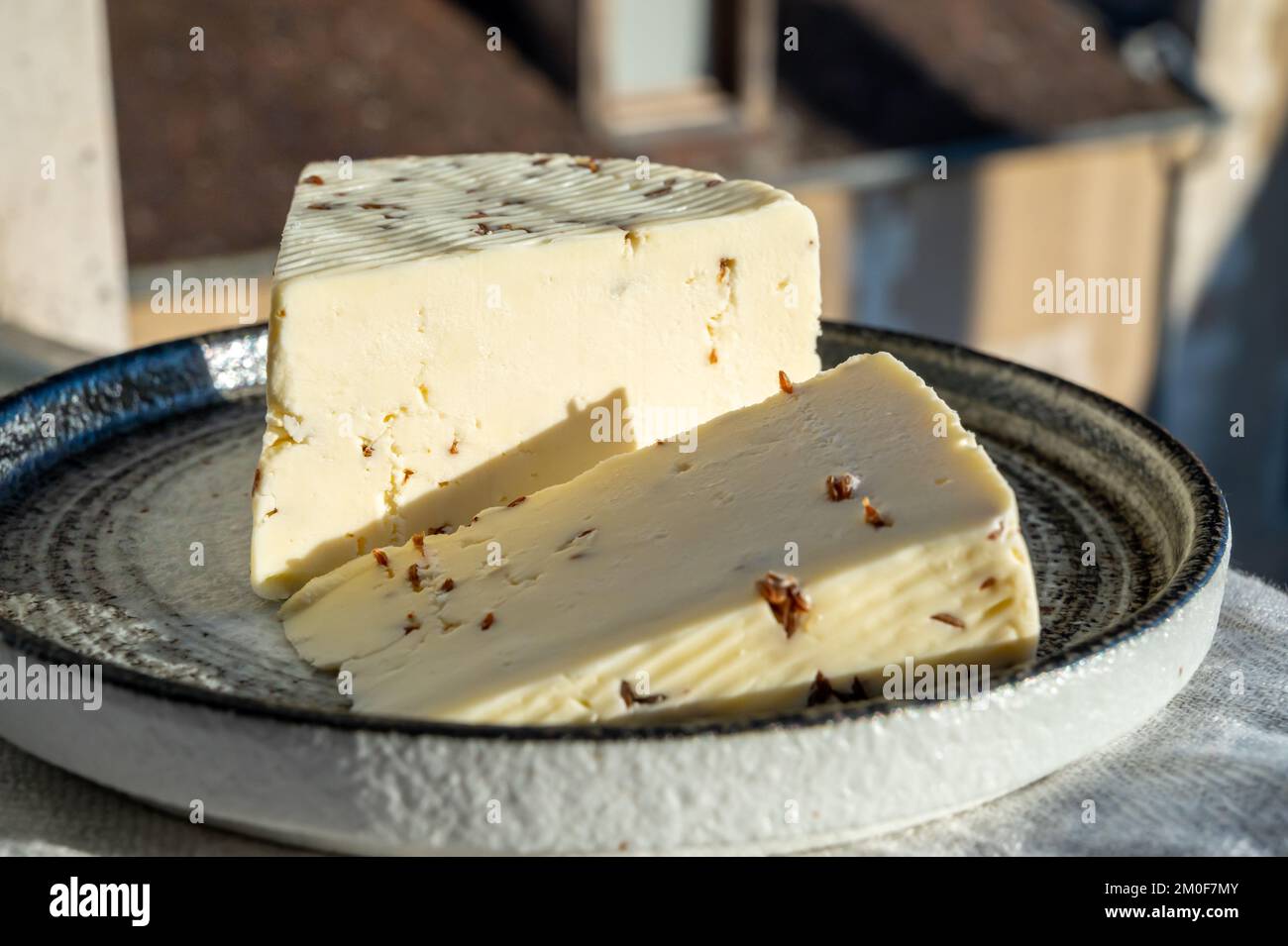 Piece of white sheep cheese with aromatic black cumin seeds served outdoor Stock Photo