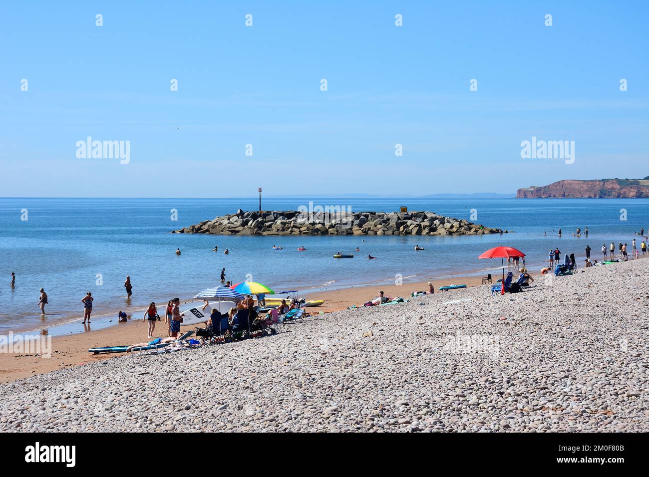 Tourists relaxing on the beach with views towards the cliffs, Sidmouth, Devon, UK, Europe. Stock Photo