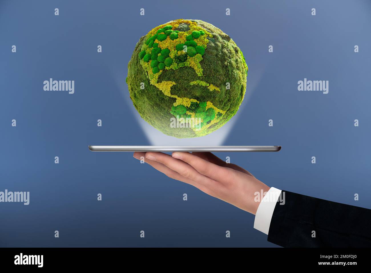A man is holding a digital tablet. Above this green planet Earth. Symbol of sustainable development and renewable energy Stock Photo