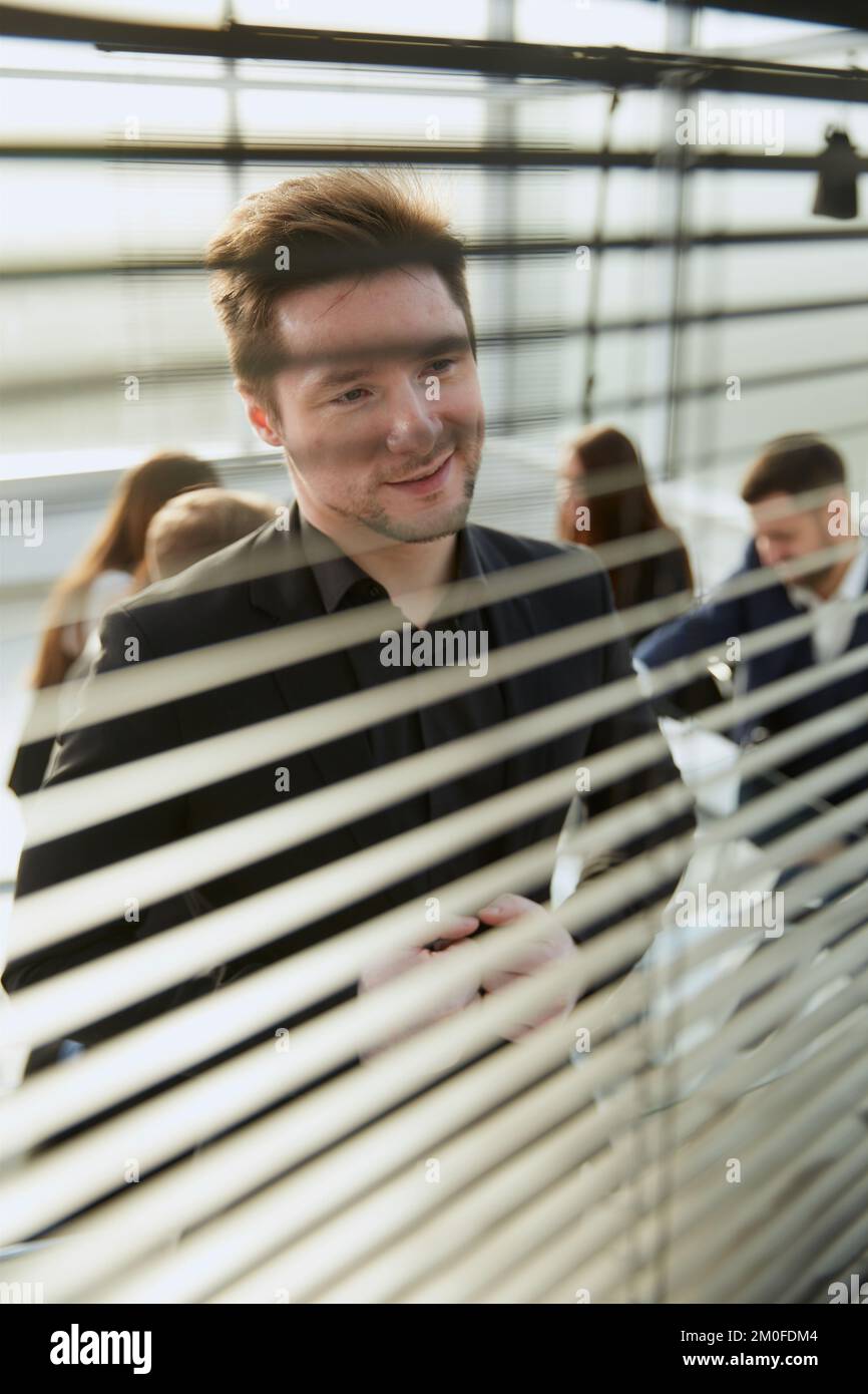 close-up-smiling-employee-looking-through-office-blinds-stock-photo