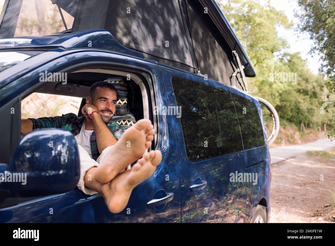 man relaxing sitting on the seat of his camper van Stock Photo