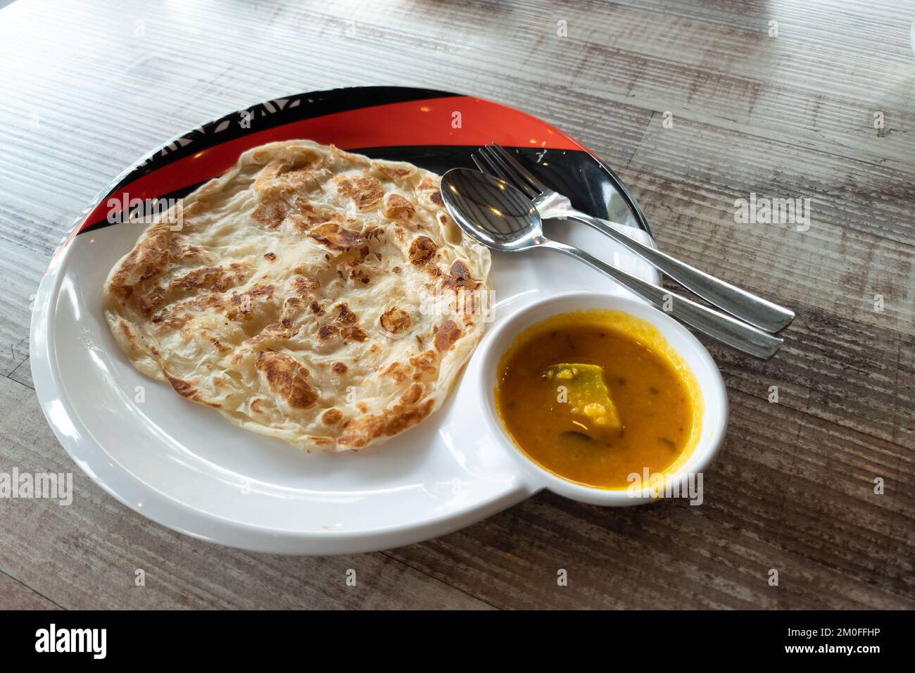 Close-up of simple no frills roti canai with dhal curry on wooden table Stock Photo