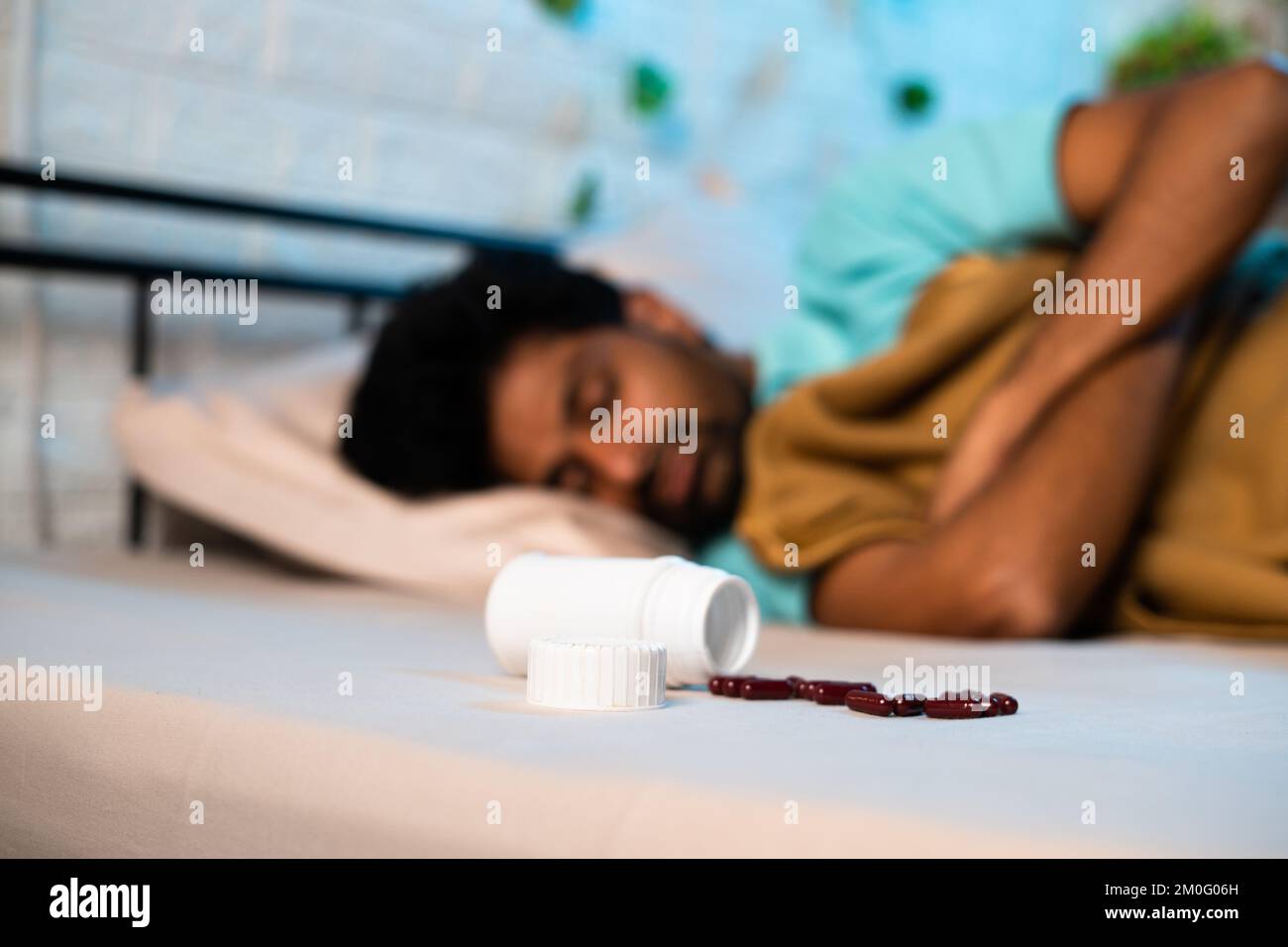 Young man in deep sleep with tablets or medicine pills on bed at night - conept of insomnia medication, unhealthy lifestyle and addiction Stock Photo