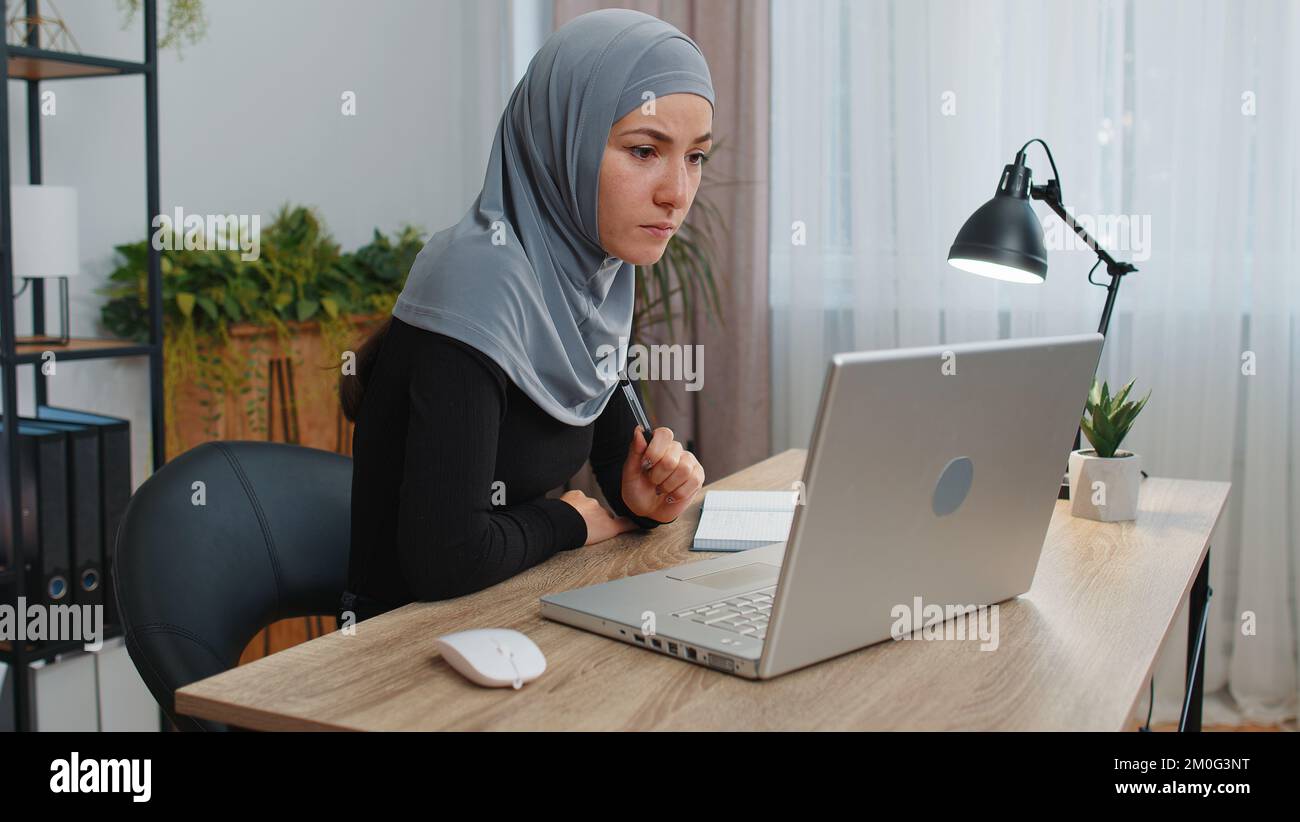 Muslim business woman in hijab study with notebook at home office on laptop computer making