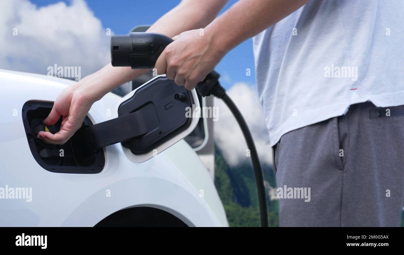 Progressive man recharge electric vehicle installing power cable plug