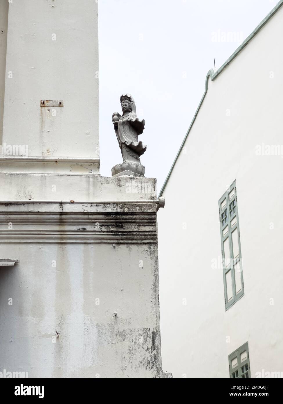 Guangyin or Goodness of Mercy statue placed on a building exterior which is overlooking the street. Stock Photo