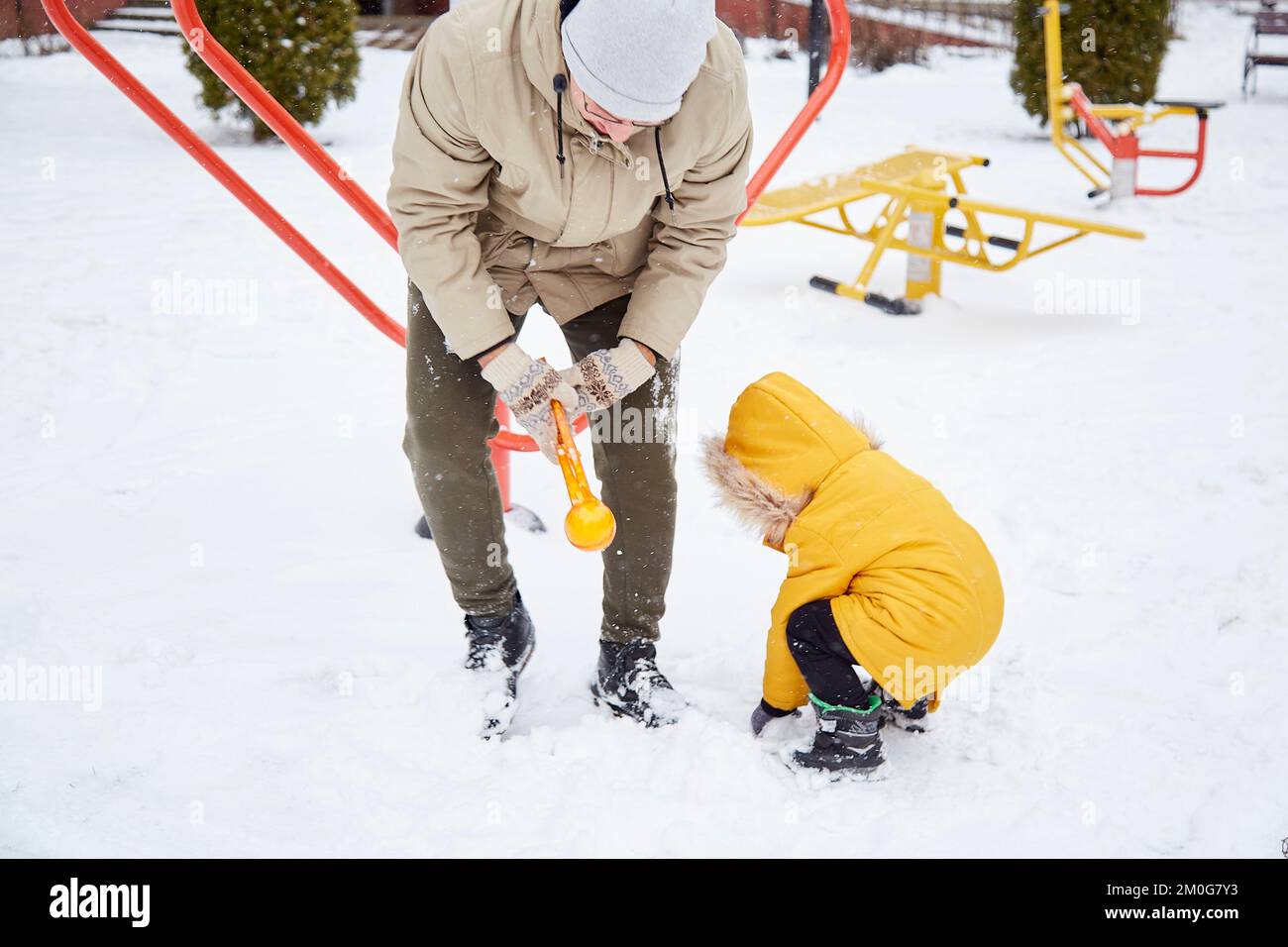 Child Making Snowballs Father and son making snowballs together, spending time together ...