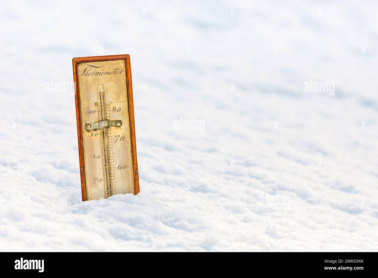 Ancient ornamental thermometer in a white snow landscape Stock Photo