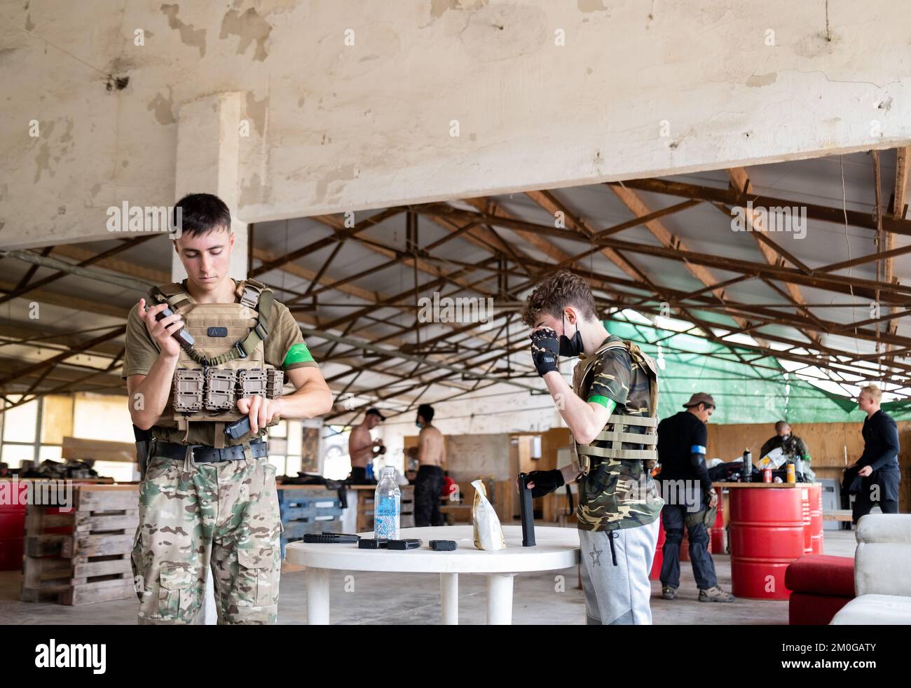 Teenagers loading ammunition during a break in an airsoft game. Stock Photo