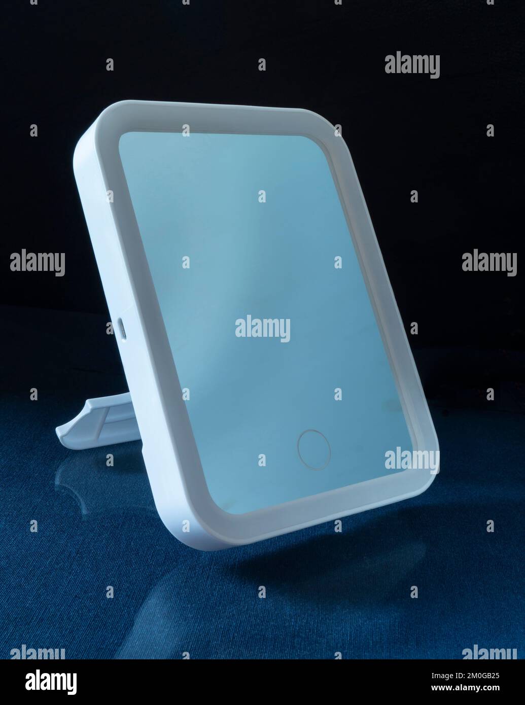 The mirror is illuminated along the contour. Household items on a black background Stock Photo