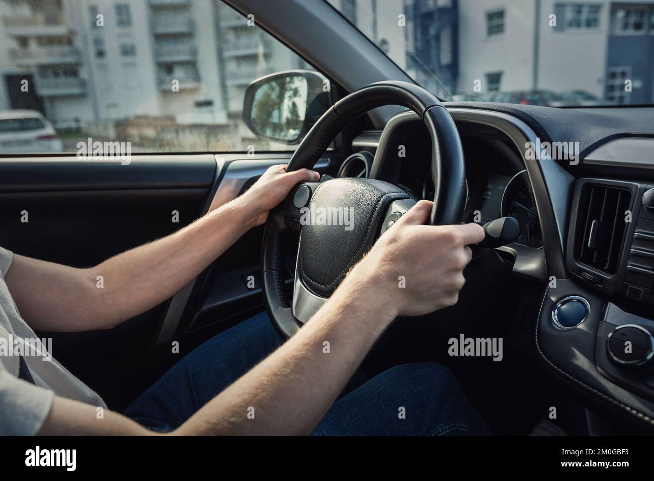 Man driving his new car stands in front of the steering wheel, closeup confident driver on the city streets Stock Photo