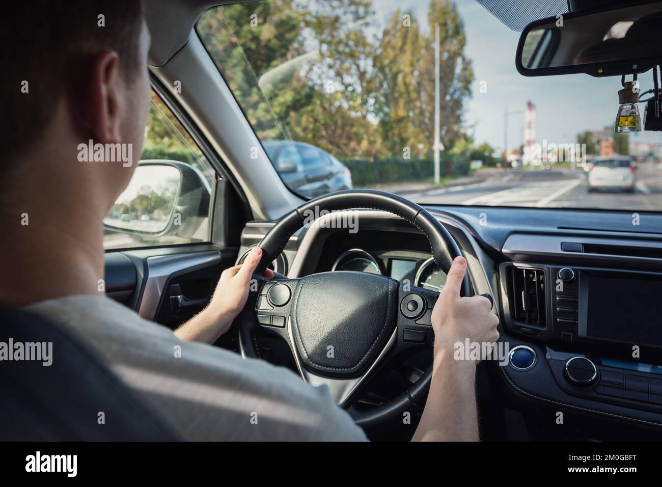 Person driving his car on the city street, close up of people hands on the steering wheel Stock Photo