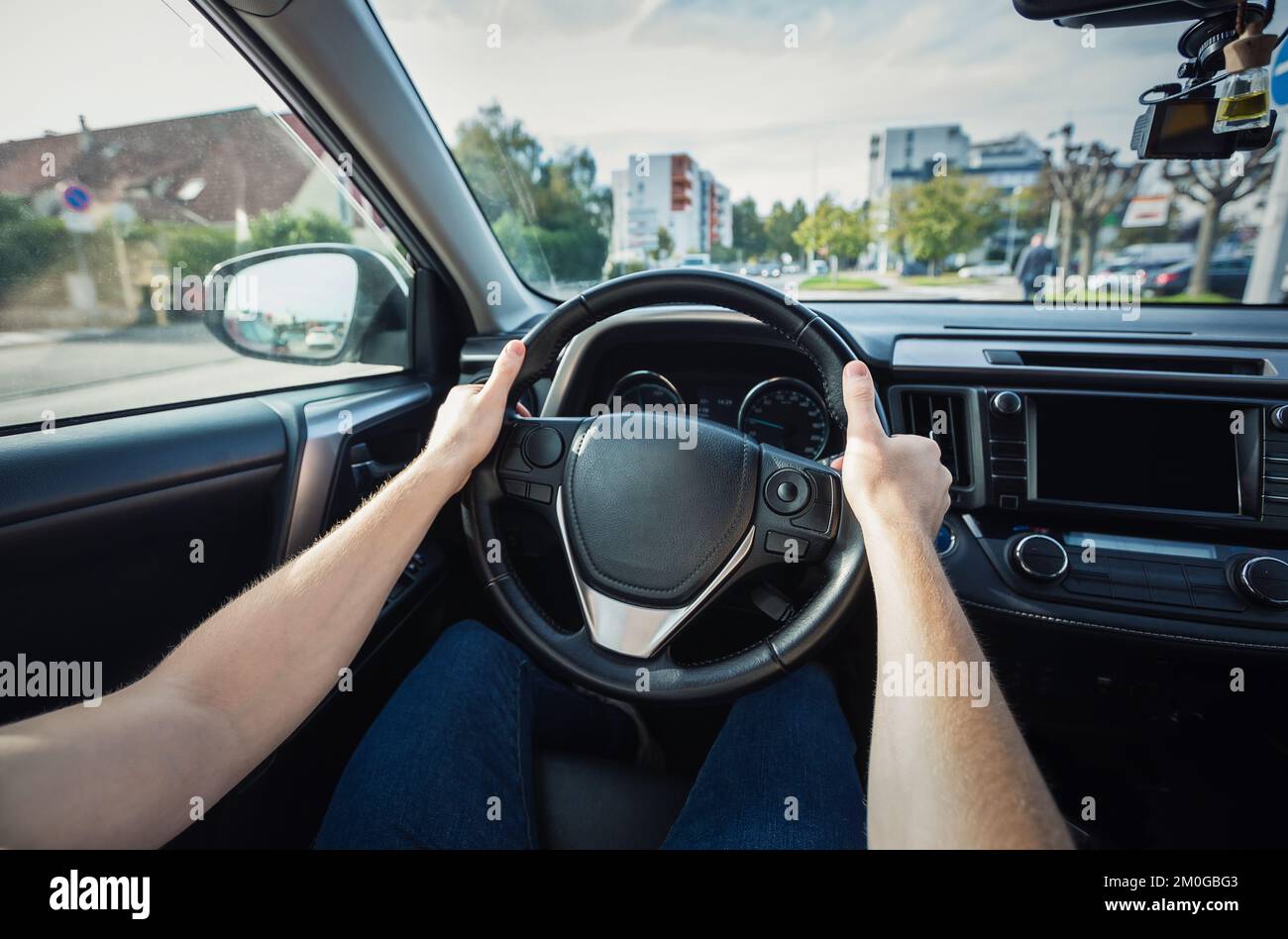 Closeup person hands on the steering wheel, confident driving car on the city streets Stock Photo