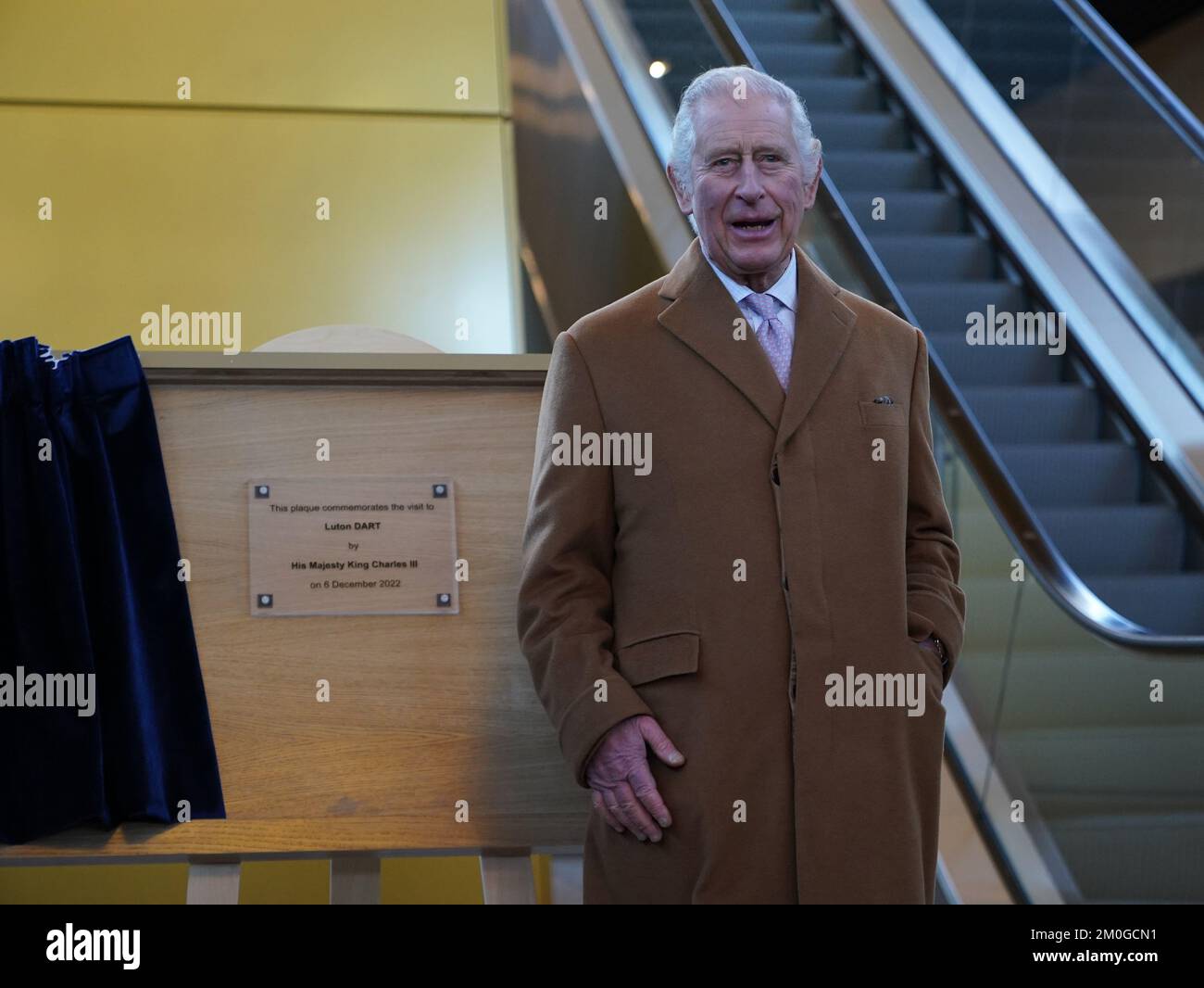 King Charles III unveils a plaque during a visit to Luton Airport to