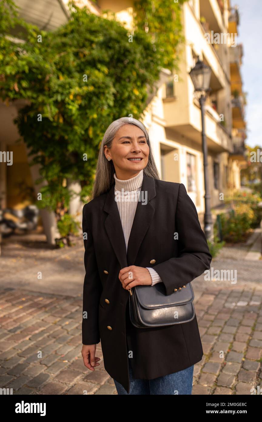 Smiling pretty woman in a black coat in the city street Stock Photo