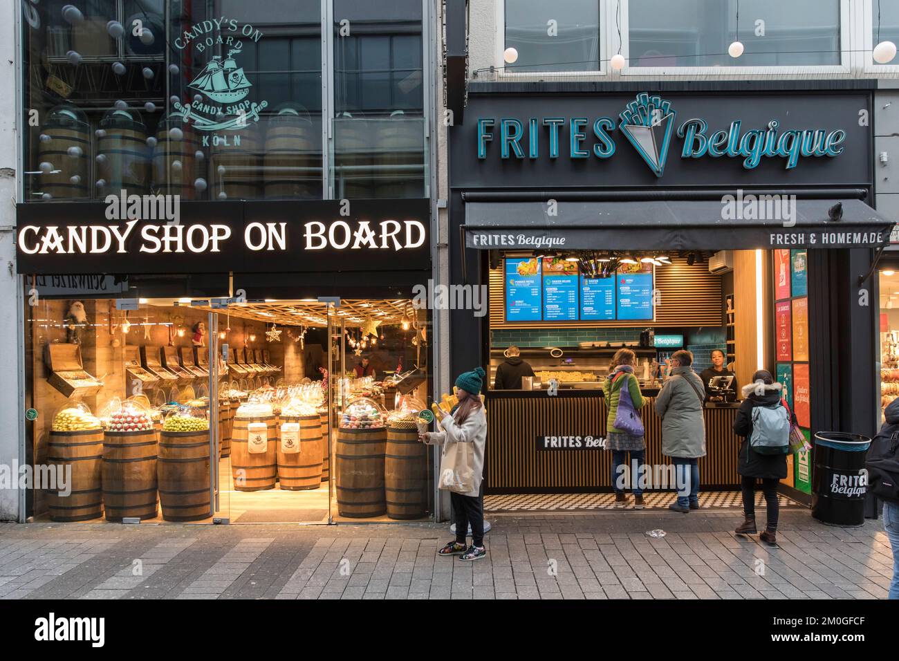 Candy Shop on Board and Frites Belgique on shopping street Hohe Strasse, Cologne, Germany. Suesswarengeschaeft Candy Shop on Board and Frites Belgique Stock Photo