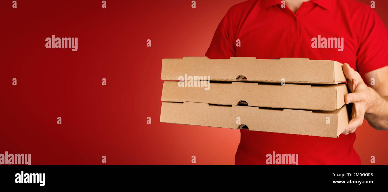 delivery man holding pizza boxes on red background. food delivery service. banner with copy space Stock Photo