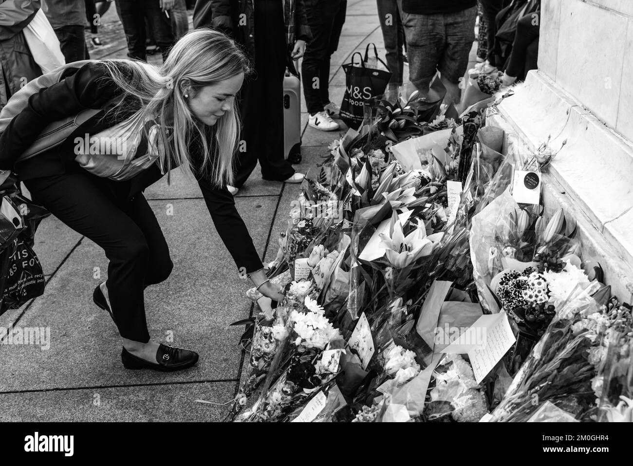 A Young Woman Lays Down A Floral Tribute Opposite The Gates Of Buckingham Palace After The Death Of Queen Elizabeth II, London, UK. Stock Photo