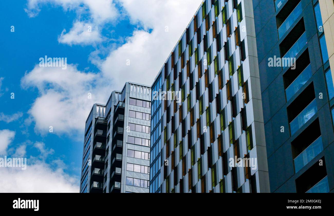 A low angle shot of a glass office building under blue sky with white ...