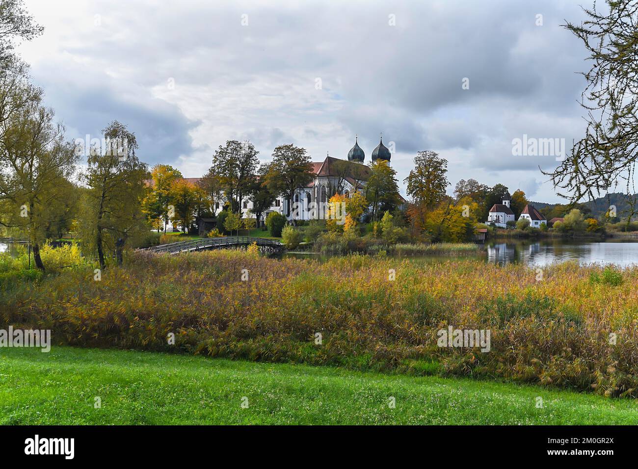Seeon Monastery with St. Lambert's Monastery Church, on the left a wooden bridge over the Klostersee, Seeon, Chiemgau, Bavaria, Germany, Europe Stock Photo