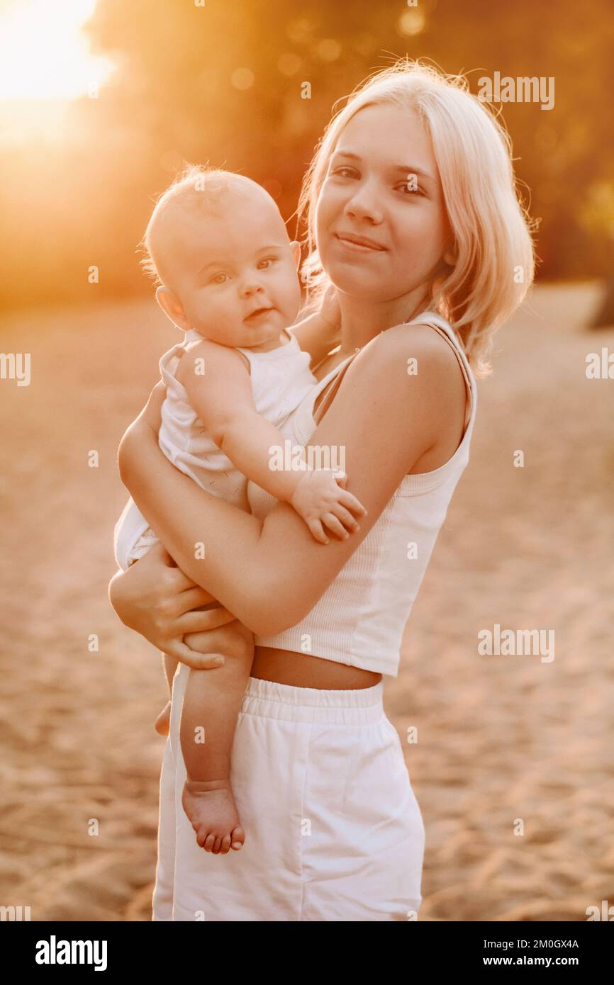 A mother holds a happy baby boy in her arms in a summer park Stock Photo