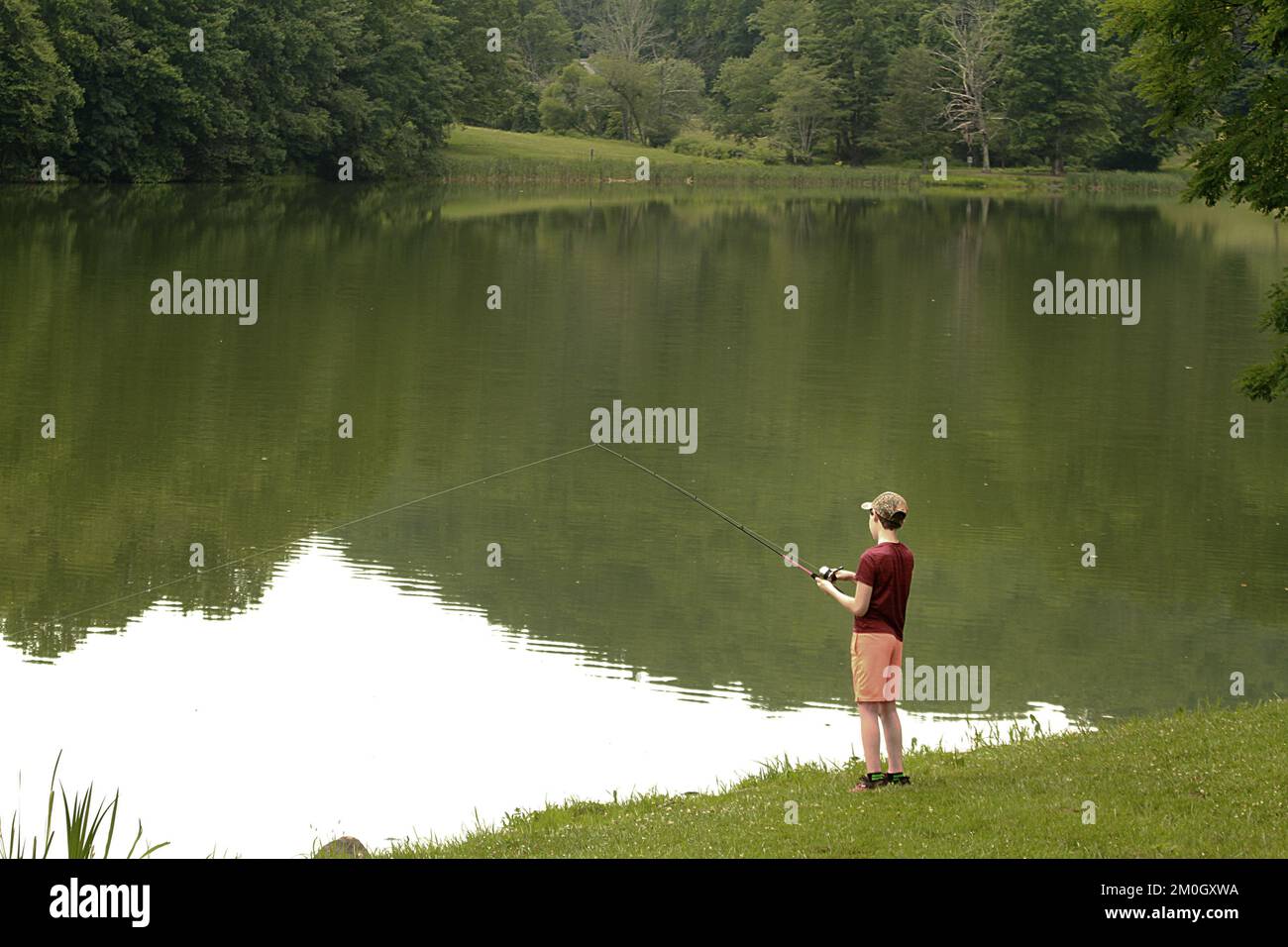 Boy casting fishing line into lake on a summer day Stock Photo - Alamy