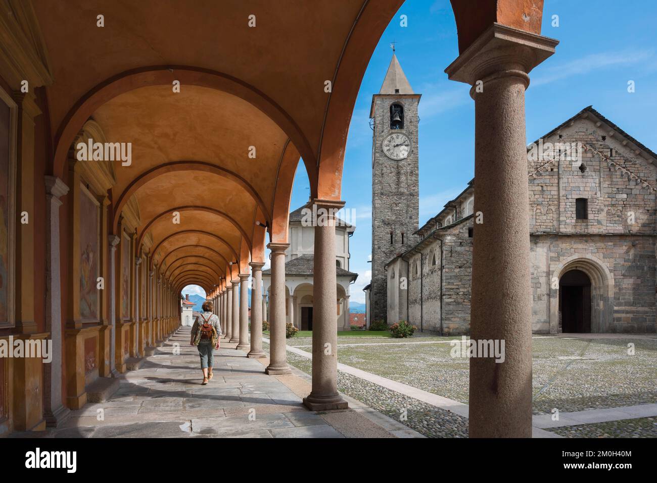 Single woman travel Italy, rear view in summer of a female traveler wearing a backpack walking under a Renaissance colonnade in an Italian town,Europe Stock Photo