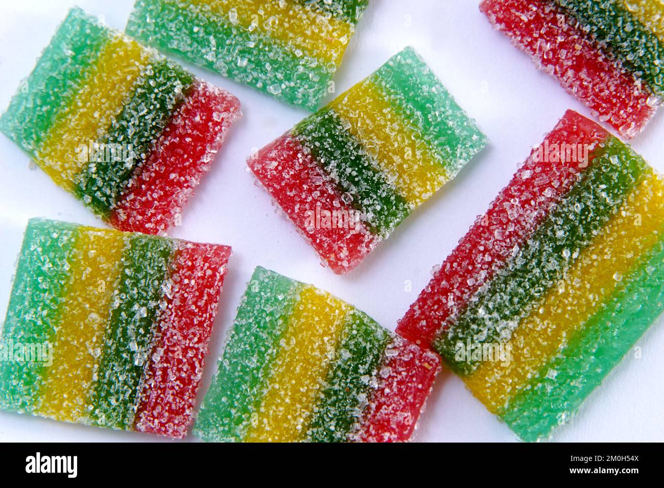 Rainbow stripes of sour jelly candies in sugar sprinkles on a white