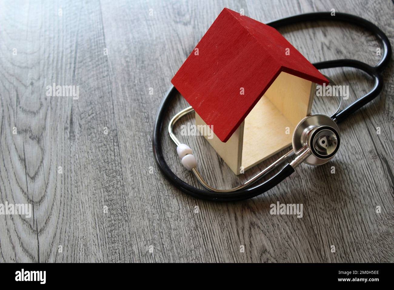 Stethoscope and house on wooden table. House inspection, repairing and diagnostic concept Stock Photo