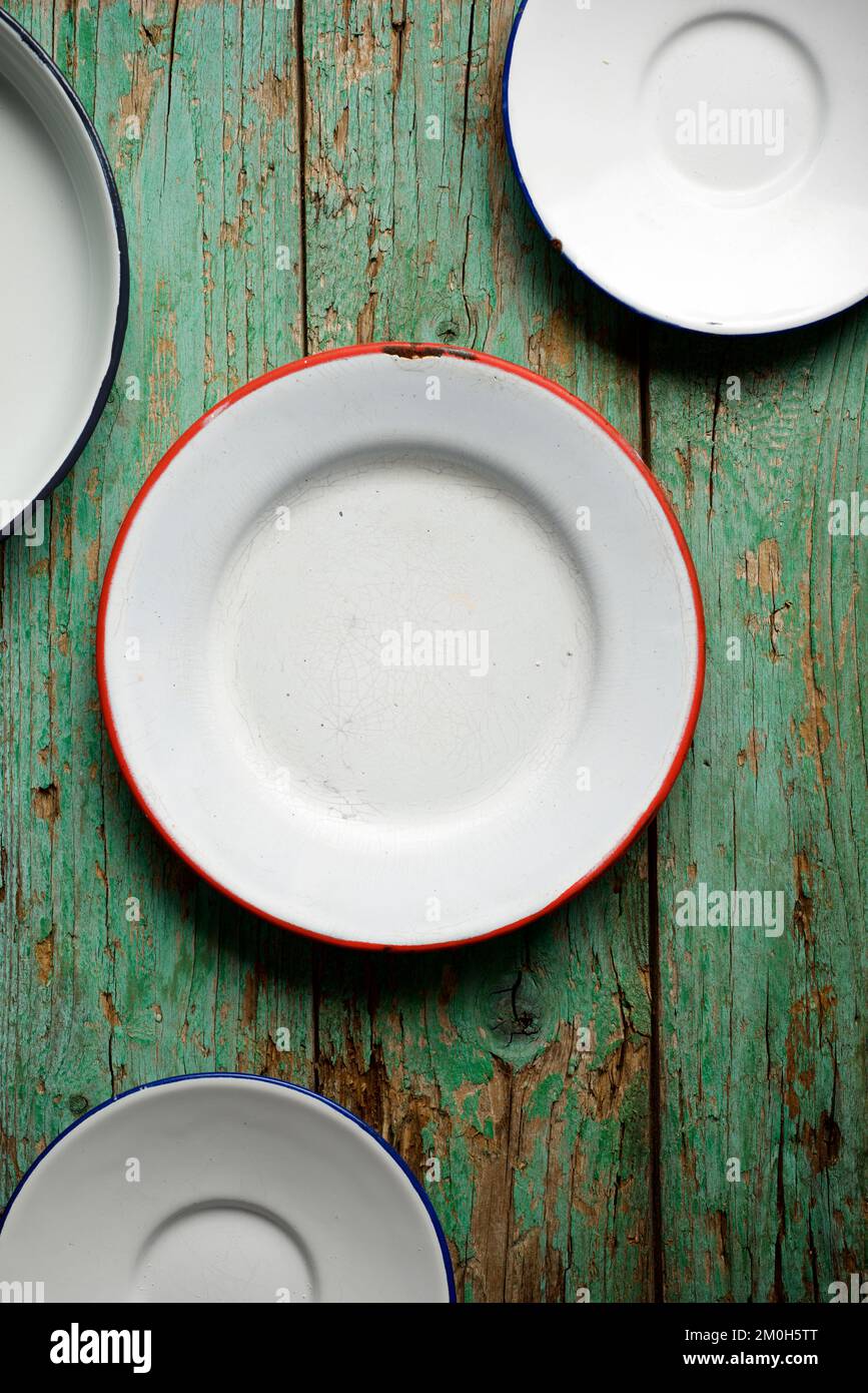 White lacquered metal plates on a green wooden table. Stock Photo