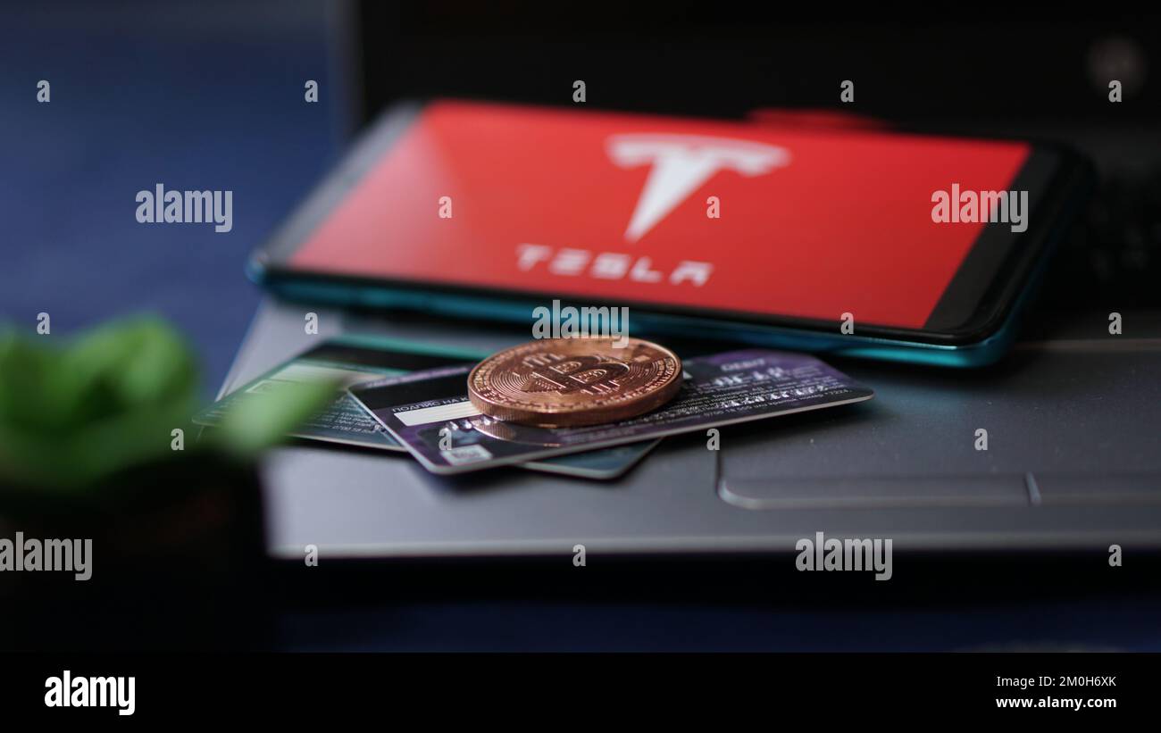 Dobrich, Bulgaria – 2022, November, 26: Mobile phone on a laptop with the Tesla logo, Bitcoin and credit cards. Illustrative editorial concept Stock Photo