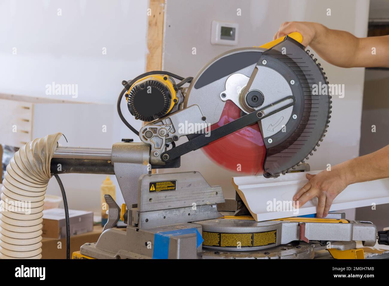On circular saw, construction worker cuts wood moldings boards as part