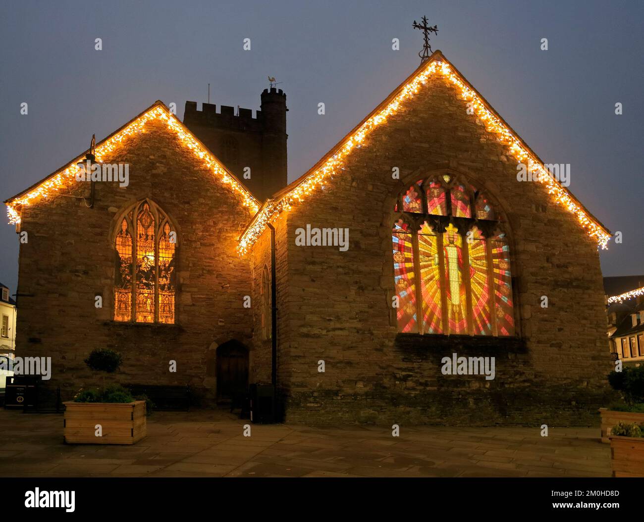 St Mary's Church, Brecon lit from within, showing stained glass windows. Jesus Christ.Brecon town, decorated for Christmas. Taken December 2022. Stock Photo