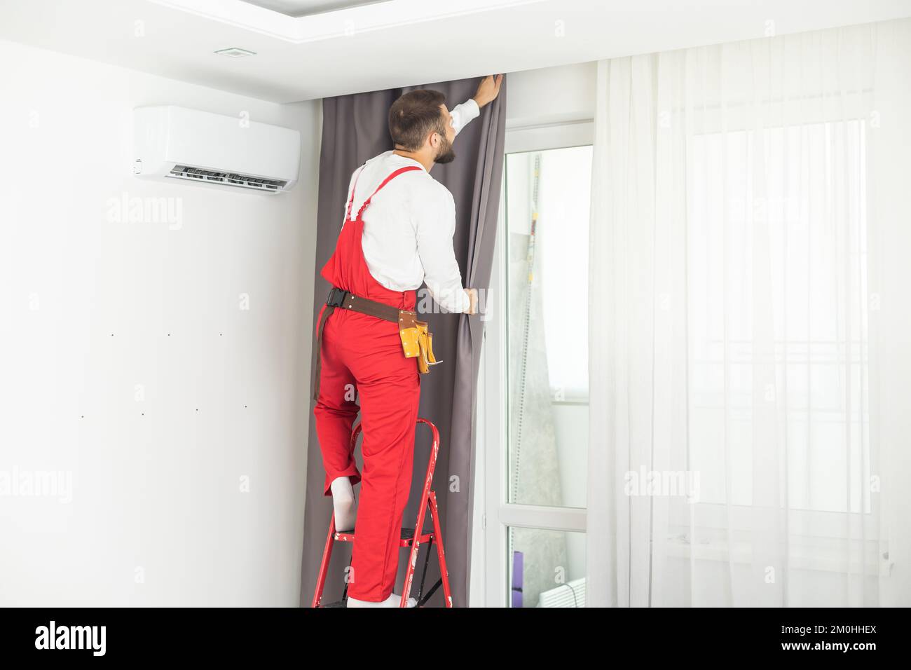 Young man installing curtains over window. Stock Photo