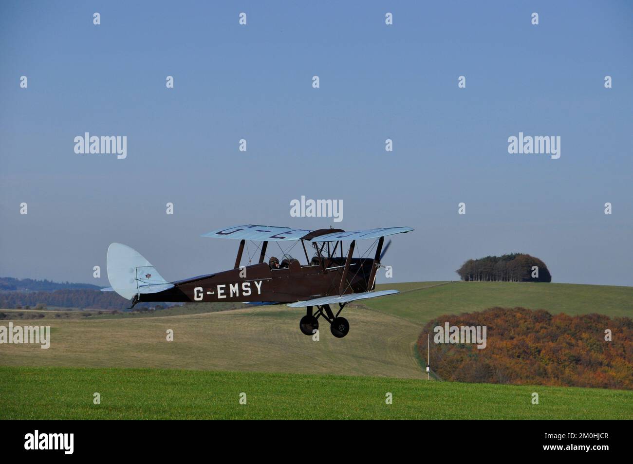 A De Havilland Tiger Moth biplane taking off from Compton Abbas airfield into beautifull clear blue sky.Near Shaftesbury in Dorset. Stock Photo