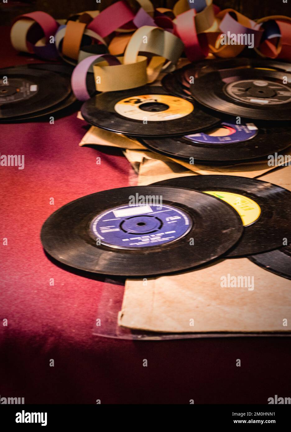 A pile of old fashioned 45 single vinyl records and coloured paper chain. Stock Photo