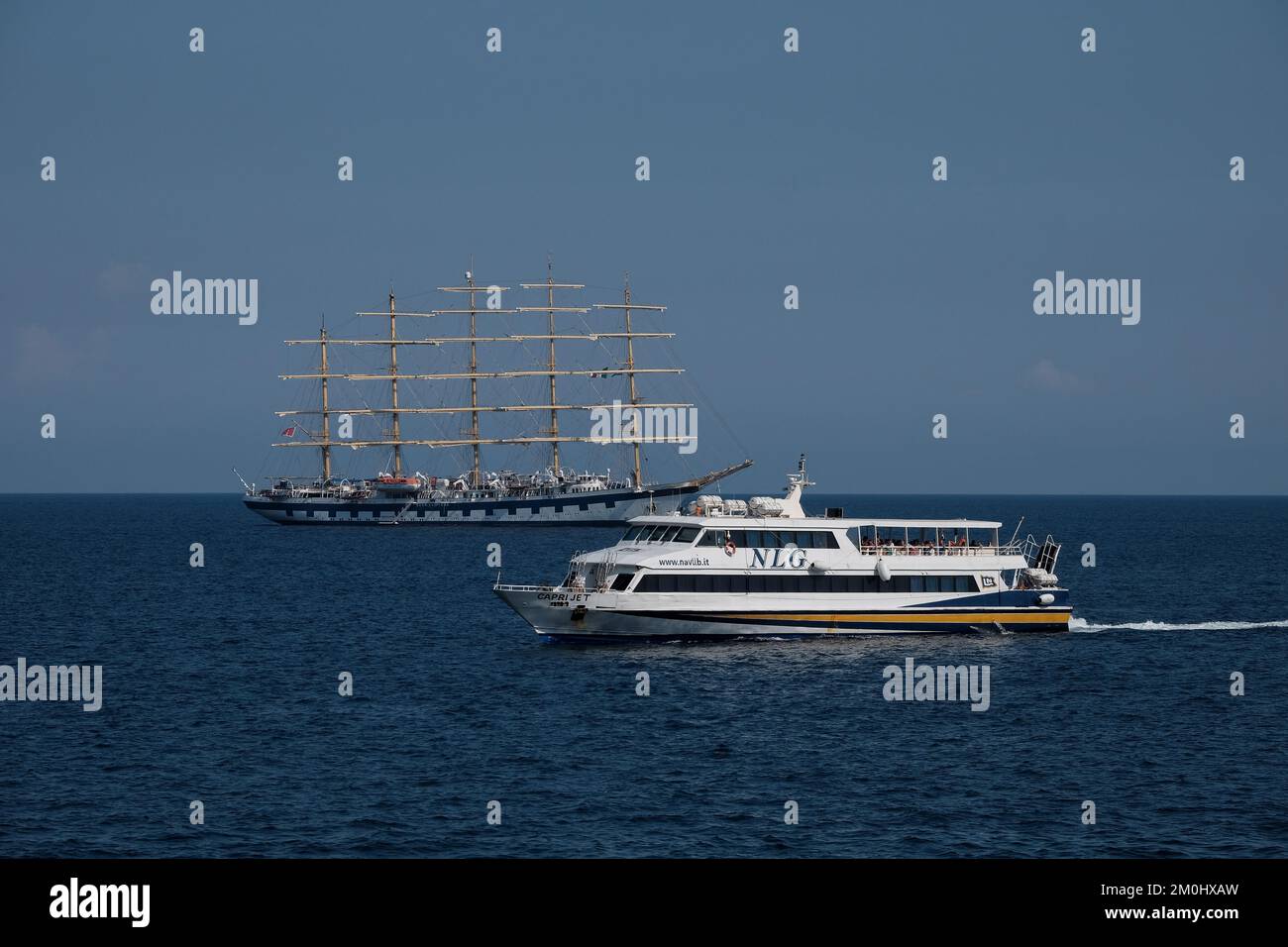 The Royal Clipper tall ship seen off the Amalfi Coast close to Positano Italy passed by a NLG Capri jet. Stock Photo