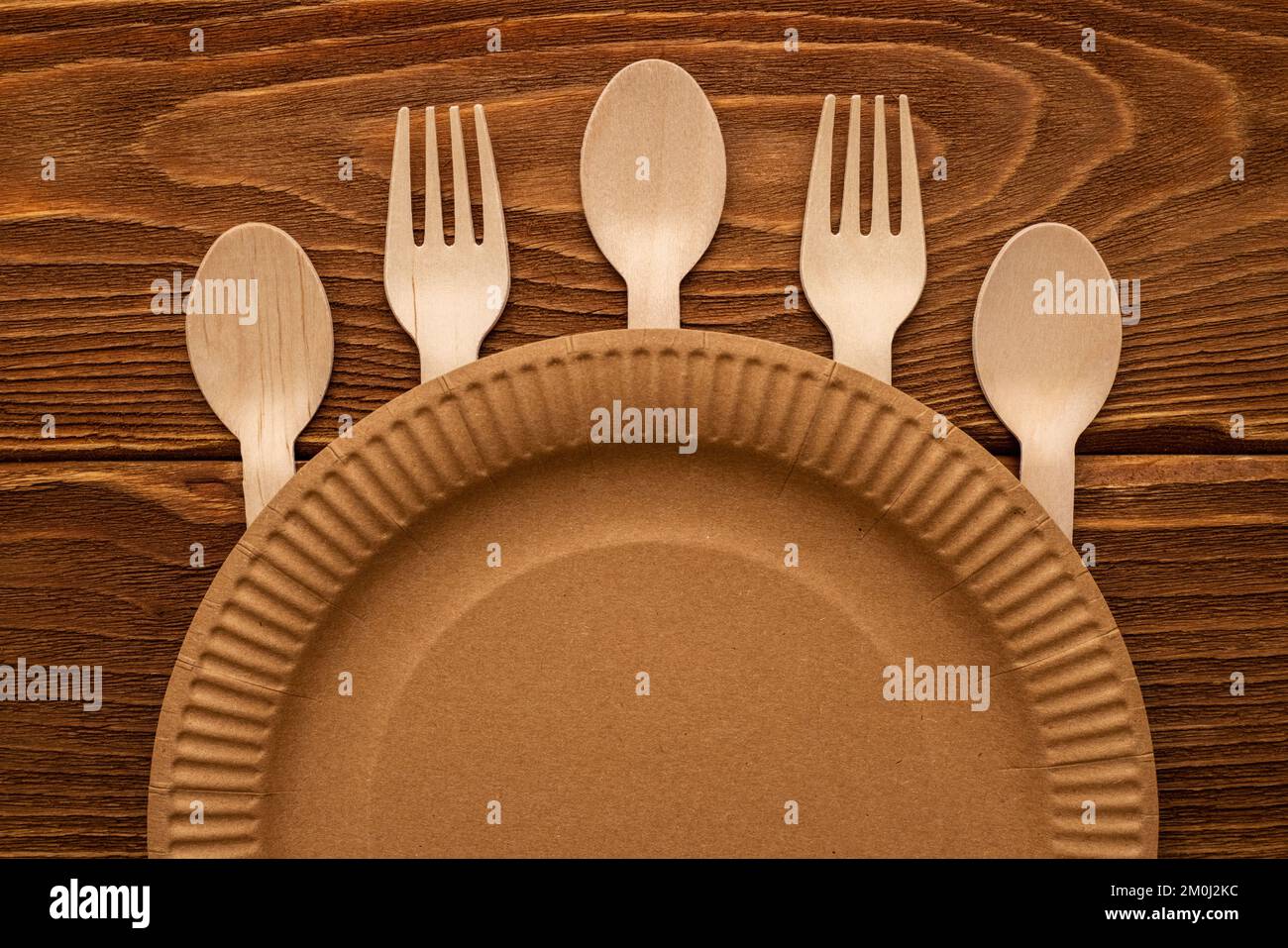 Wooden forks and spoons and paper plate on wooden background Stock Photo