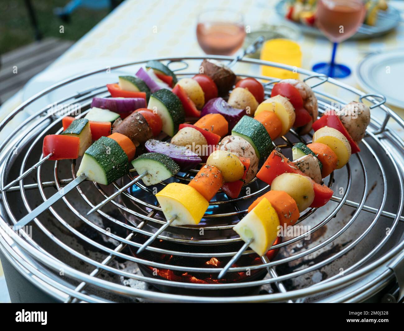 Skewers with mixed vegetables (zucchini, potato, carrot, bell pepper, mushroom) cooking on a charcoal grill Stock Photo