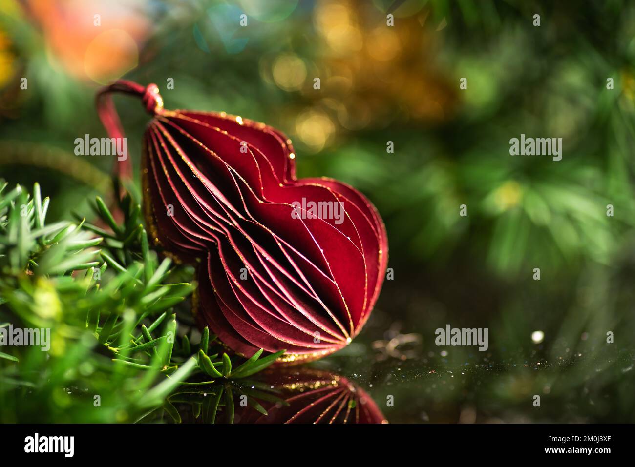 Festive winter holiday decoration and the Christmas tree with shiny fairy lights in the background Stock Photo