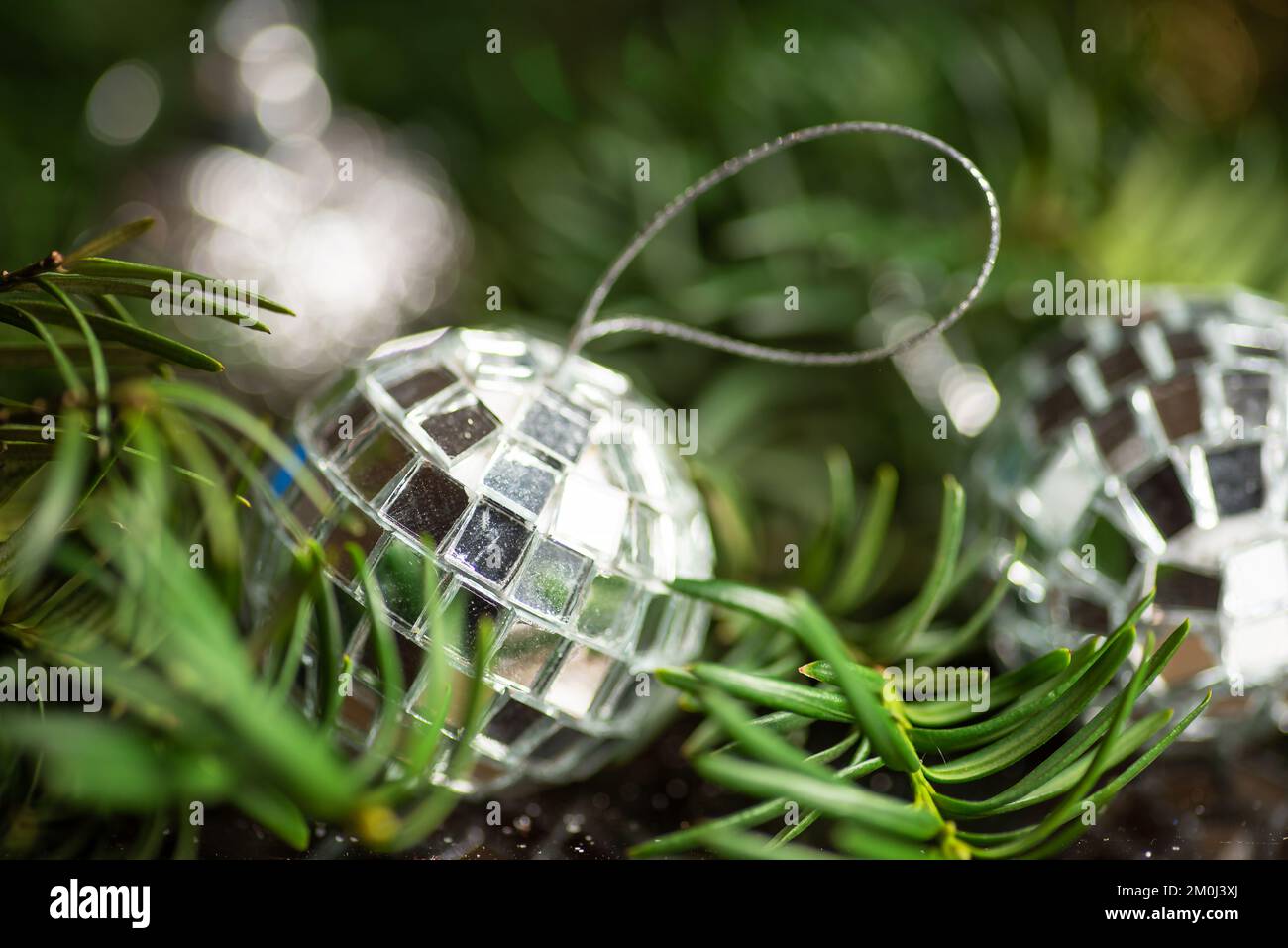 Festive winter holiday silver decoration and the Christmas tree with shiny fairy lights in the background Stock Photo