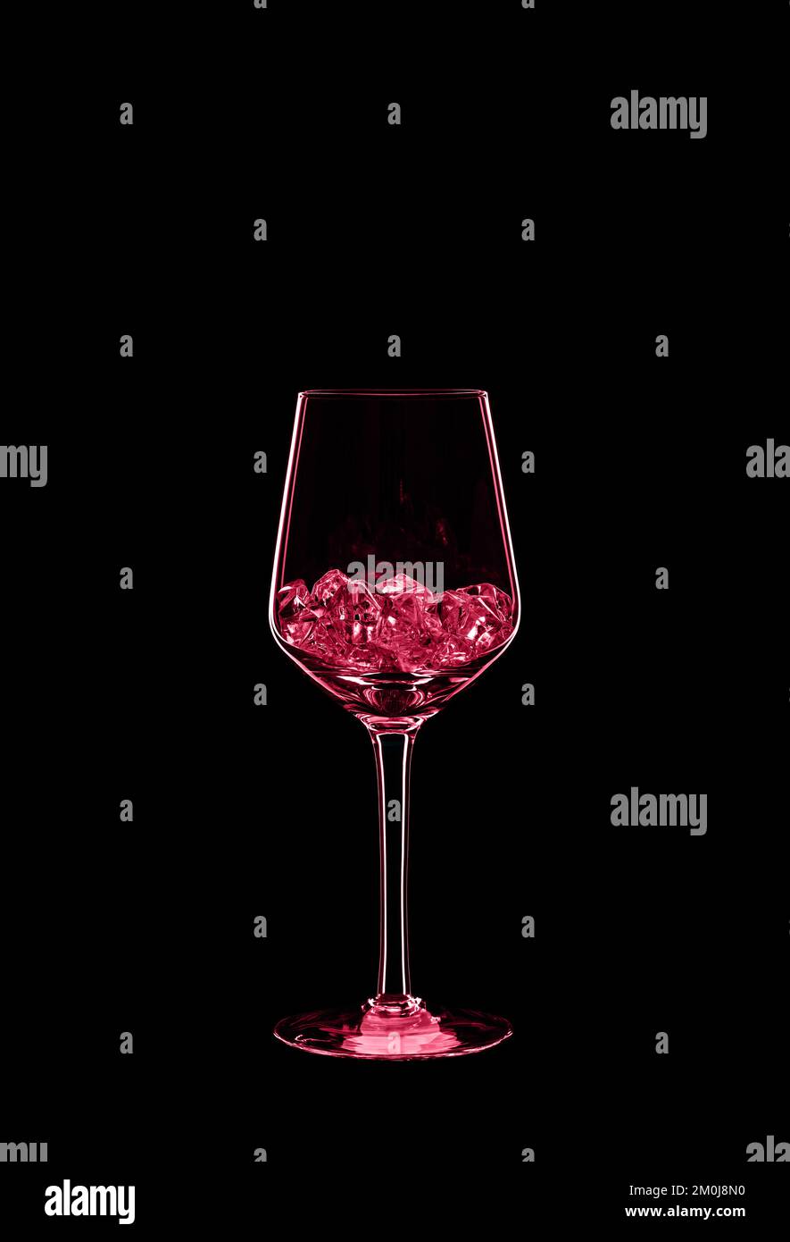 Wine glass filled with transparent crystals backlit and isolated on black background. Toned