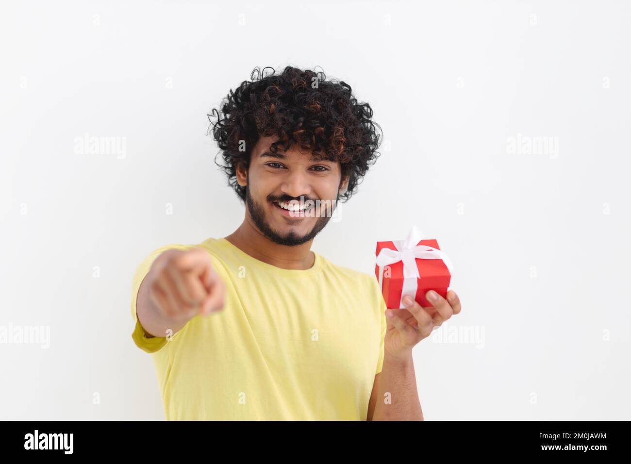 Asian man with curly hair hold red gift box toothy smile looking at camera on white background Stock Photo