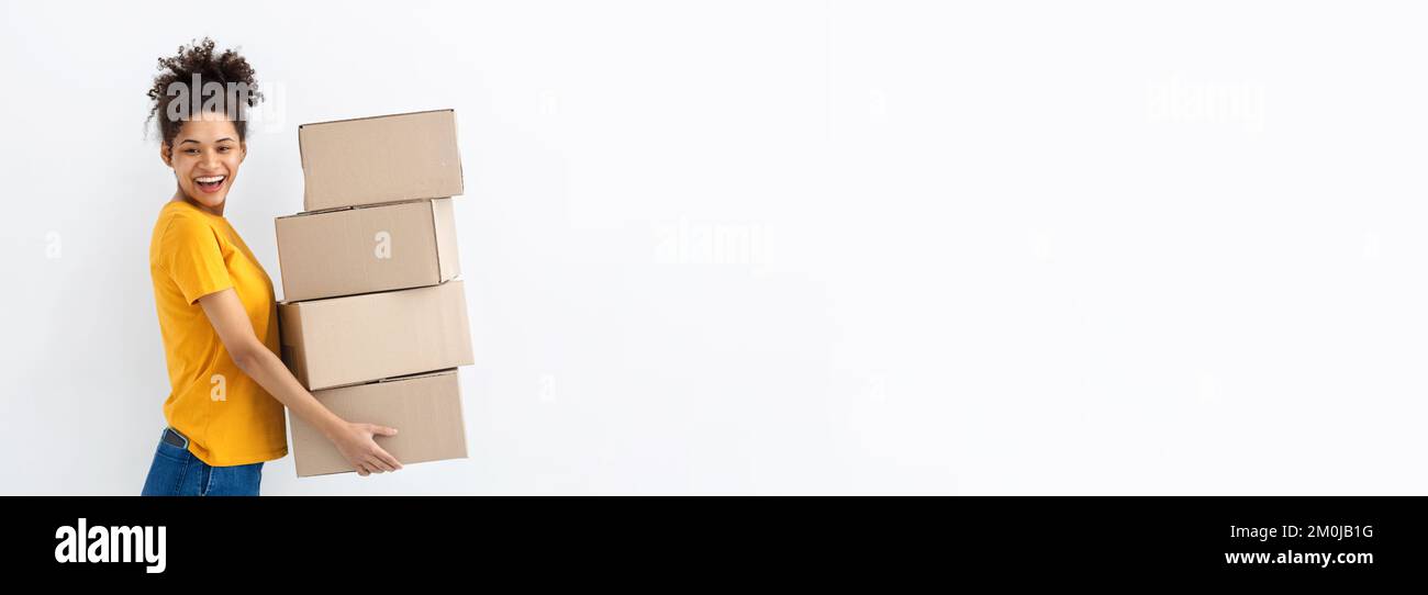 Young happy African American woman with stack of cardboard boxes on white background Copy space Stock Photo